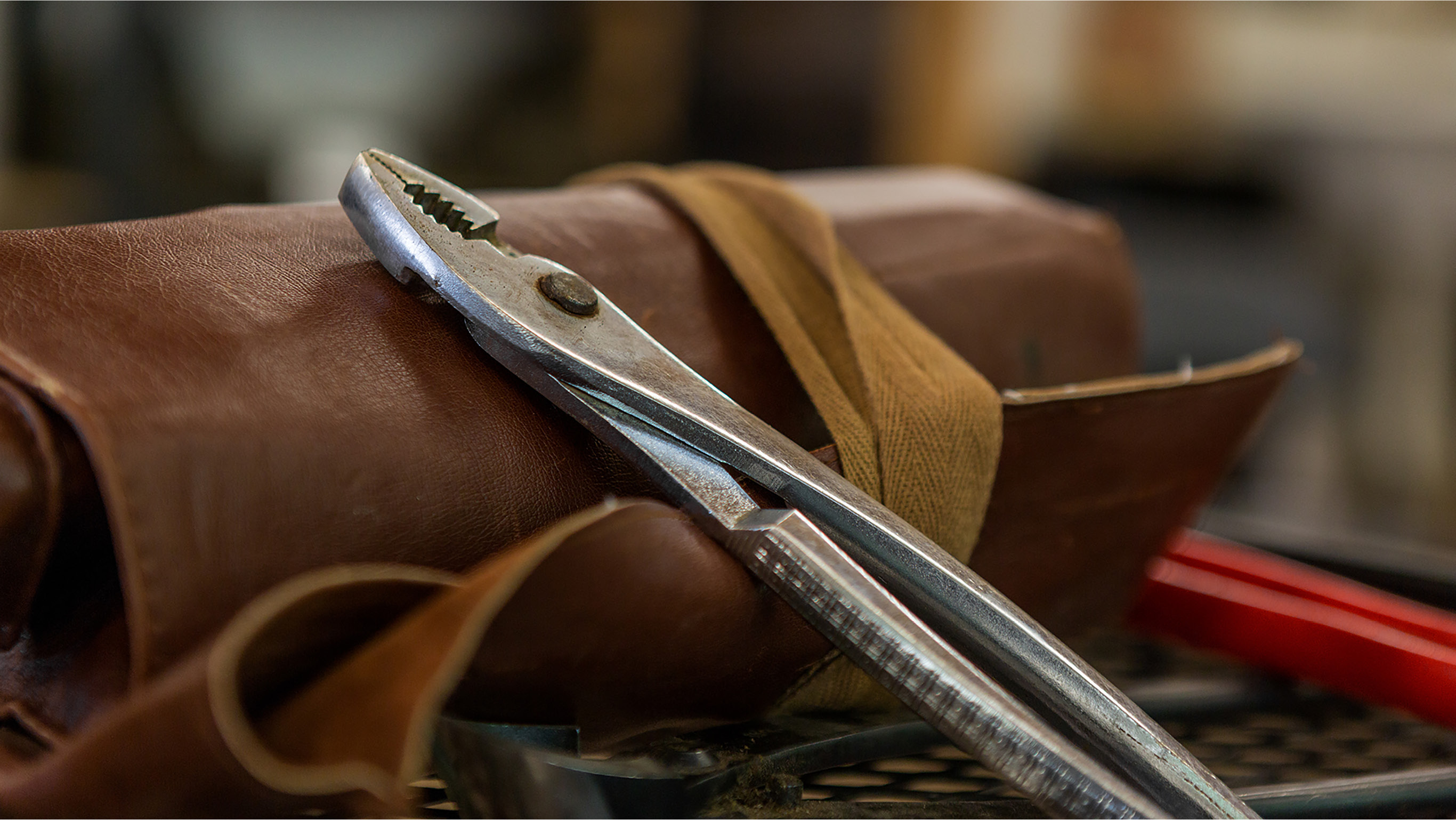 A photo of pliers on top of a leather bonsai tool bag.